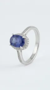Anillo de plata 925 con piedra central ovalada en color azul zafiro, rodeada de pequeñas circonias y pavé de circonias en los hombros.