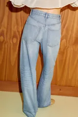 Jeans de tiro alto con diseño de pierna extra ancha y larga. Presenta cinco bolsillos, cierre frontal con cremallera y botón metálico, con un acabado de lavado desgastado.
