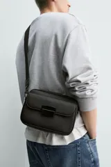 Bandolera de diseño compacto con acabado texturizado, compartimento principal con cierre de cremallera, bolsillo frontal con cierre magnético y correa ajustable y extraíble.