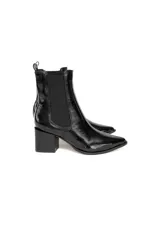 Botas de caña baja tipo chelsea de cuero charol negro con acabado brillante, punta fina y taco cuadrado. Cuentan con paneles elásticos laterales y presilla trasera.