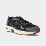 Championes New Balance 530 de estilo retro running, color negro y gris con entresuela blanca y suela de goma marrón, confeccionados con malla transpirable y refuerzos sintéticos.