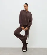 Pantalón deportivo de corte flare, color marrón, con cintura elástica y diseño liso. Presenta una abertura lateral en el bajo.