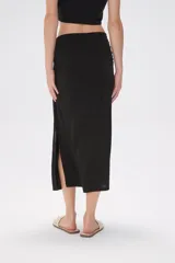 Falda midi de corte tubo confeccionada en modal, con detalle de frunces laterales que aportan movimiento y ajuste al cuerpo.