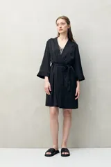 Bata de pijama negra de tejido satinado con leve elasticidad, silueta fluida y estilo envolvente. Presenta diseño cruzado con lazo regulable en la cintura y mangas amplias.