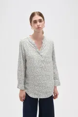 Blusa de viscosa con estampado floral pequeño, cuello mao con escote en V y cierre frontal parcial de botones. Presenta mangas largas con puños y un bolsillo frontal en el pecho.