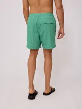 Short de baño color azul, con cintura elástica y cordón ajustable. Presenta un parche pequeño con logo en la parte inferior de la pierna.