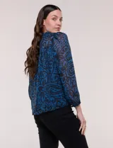Blusa de silueta holgada y caída fluida, confeccionada en gasa liviana con estampado paisley en tonos azules y negros. Presenta cuello mao con escote en V, cartera frontal con botones, canesú con frunces y mangas largas con puños elastizados.