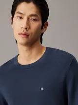 Sweater de cuello redondo Calvin Klein confeccionado en algodón orgánico con textura de micro piqué. Presenta puños y dobladillo en punto canalé y el logo de la marca bordado en el pecho.