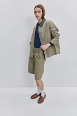 Campera de gabardina tostada, con cuello camisero de pana marrón, cierre frontal de botones metálicos y bolsillos delanteros aplicados con solapa.