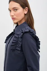 Camisa de gabardina de tencel color negro, con cuello clásico, cierre frontal de botones y volados fruncidos en los hombros.