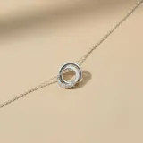 Tobillera de plata 925 con dijes pasantes en forma de dos aros entrelazados, uno de ellos decorado con circonias brillantes.