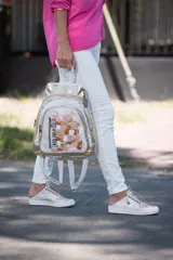 Mochila de cuero blanca y dorada con diseño texturizado tipo cocodrilo y detalles de arte abstracto en tonos nude y rosa. Cuenta con múltiples compartimentos con cierre y herrajes metálicos en oro viejo.