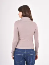 Polera de tejido de punto fino, con cuello alto doblado y mangas largas. Presenta un diseño ajustado al cuerpo con terminaciones acanaladas en puños y ruedo.