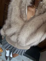 Campera de piel sintética en tono beige, con diseño de cuello alto y cierre frontal completo. Presenta una base de tejido liso en la parte inferior y puños ajustados.