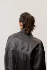 Camisa de cuero color negro, de manga larga con puños abotonados, cierre frontal con broches metálicos y un bolsillo aplicado en el pecho.