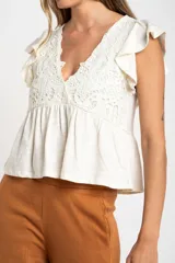 Remera color crudo de algodón con calados, corte al cuerpo y mangas cortas con volados.