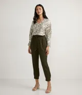 Blusa de crepé color blanco con estampado de hojas verdes, escote en V y mangas largas abullonadas con detalle de nudo en los puños.