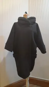 Chaquetón negro de lana tipo astracán, modelo oversize con cuello y puños de piel sintética. Cierre con un botón. Talle único hasta 2XL.