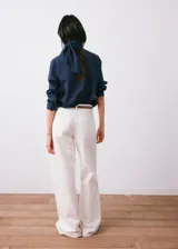 Blusa de cuello alto con diseño de rayas verticales finas, confeccionada en una mezcla de viscosa, poliamida y poliéster. Presenta cierre frontal de botones y mangas largas con puños abotonados.
