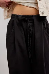 Pantalon de lino y algodon color beige, de tiro bajo, estilo relajado con cintura elastizada ajustable mediante cordón y bolsillos laterales.