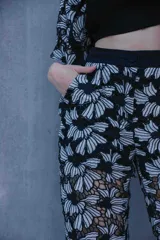 Conjunto de tres piezas compuesto por camisa de manga corta, pantalón de corte recto y top tipo bandeau. Todas las prendas presentan un diseño de encaje con estampado floral en blanco y negro.