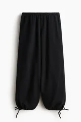 Pantalón en denim suave con cintura elástica, bolsillos laterales discretos y corte holgado con piernas globo y cordón ajustable en los bajos.
