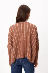 Sweater de punto con diseño de rayas verticales en relieve y textura trenzada, color terracota y beige. Presenta cuello redondo, corte holgado y diseño cropped.
