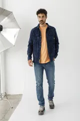 Sobrecamisa de tejido polar con estampado abstracto en tonos rojizos y azul marino. Presenta cuello clásico, cierre frontal con botones a presión, dos bolsillos frontales con solapa en el pecho y un parche decorativo.