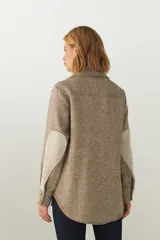 Camisa estilo leñador color beige con textura en espiga, de manga larga, con cuello clásico, cierre frontal con botones, dos bolsillos de parche con solapa abotonada en el pecho y puños abotonados. Confeccionada en lana fina sin teñir.
