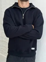 Buzo negro de felpa con cuello alto y cierre metálico plateado.