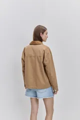 Campera de gabardina tostada, con cuello camisero de pana marrón, cierre frontal de botones metálicos y bolsillos delanteros aplicados con solapa.