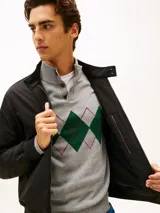 Campera tipo Harrington de Tommy Hilfiger en color negro, de corte amplio y tejido repelente al agua. Cuenta con cuello levantado, cierre frontal de cremallera con botón, bolsillos de ojal en la cintura, y puños y bajo de punto canalé. Presenta el logo de la marca bordado en el pecho.