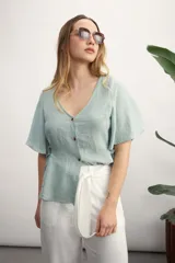 Camisa negra con botones dorados, escote en V y mangas cortas amplias con lazos laterales. 