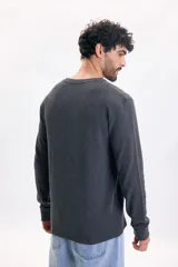 Remera de manga larga gris oscuro con textura waffle, cuello redondo y puños elásticos.