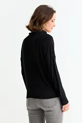 Sweater negro de cuello alto con diseño de tejido trenzado vertical y textura geométrica. Presenta mangas largas con puños acanalados y un corte holgado.