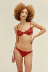 Conjunto de bikini de lycra roja con estampado de leopardo negro. El corpiño es triangular con tirantes finos y la bombacha es de corte clásico.