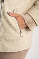Campera de textura bouclé en color tostado, con diseño de solapas amplias, cierre frontal cruzado y mangas largas. Presenta un corte estructurado y moderno.