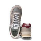 Championes urbanos New Balance modelo 574, en tonos gris y beige con detalles en bordó. Confeccionados en una combinación de gamuza y malla, presentan el logo 'N' característico en los laterales y entresuela con tecnología ENCAP para mayor amortiguación.