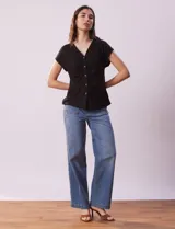 Remera de lino color negro, marca Zac & Rachel. Escote en V con abertura y botones. Delantera con frunce.