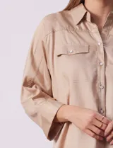 Camisola color beige de tencel, marca Hester & Orchard. Tiene cuello con solapa, escote en V, abertura central con botones y bolsillos delanteros.