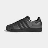 Championes Adidas Superstar II, modelo clásico de caña baja en color plateado metalizado con detalles en negro, incluyendo las tres tiras icónicas, los cordones, la suela y el refuerzo del talón. Cuentan con la tradicional puntera de caucho con relieve y exterior de cuero.
