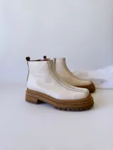 Botas Chelsea de cuero color crudo con elástico lateral, suela track color caramelo y tirador trasero de cuero con textura croco color marrón.