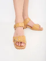 Sandalias de cuero color ocre con doble tira sobre el empeine y hebillas metálicas plateadas. Suela de goma con plataforma baja y detalle de costuras.