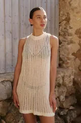 Vestido corto tejido calado color crudo, sin mangas y con escote redondo.
