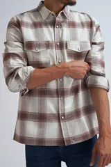 Camisa de manga larga con estampado de cuadros en tonos beige y marrón, confeccionada con cierre frontal de botones y bolsillos en el pecho.