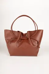 Bolso tipo tote bag negro de cuero sintético, con frunce superior ajustable con cordones y doble asa de hombro.