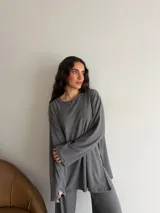 Conjunto oversize de dos piezas en tejido acanalado color beige, compuesto por una remera de manga larga con aberturas laterales y un pantalón largo de corte recto y holgado.