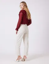 Pantalón sastrero color beige, de corte recto y tiro alto, con largo al tobillo. Tiene pretina limpia con cierre interno y pasadores, y bolsillos funcionales en la parte delantera.