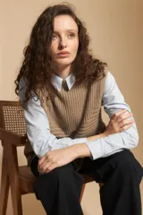 Chaleco de tejido de punto en color crema, con cuello alto y diseño acanalado. Presenta una silueta relajada con aberturas laterales.