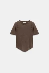 Camiseta de cuello redondo y manga corta con efecto lavado. Presenta detalle de tachas metálicas en el escote y bajo asimétrico.